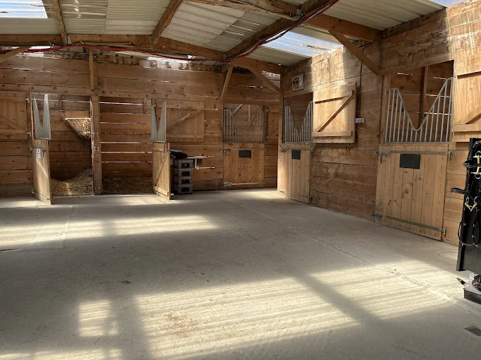 Intérieur des écuries d'Oska, boxes en bois et allée centrale